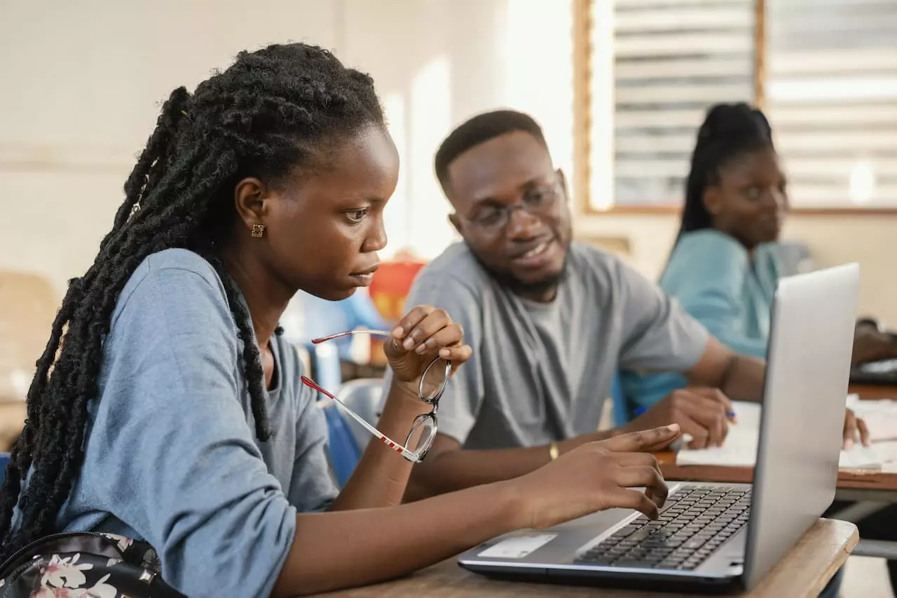 Étudiants concentrés travaillant ensemble sur un projet avec un ordinateur portable dans une salle de classe